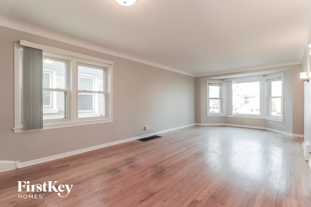 A room with wooden floors and two windows.