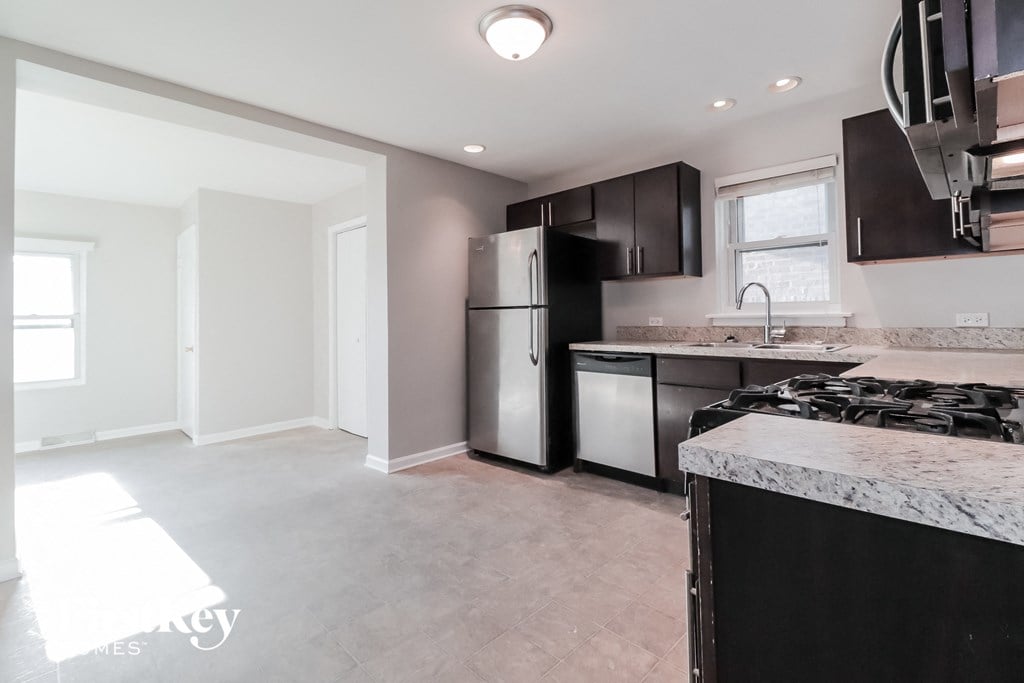A kitchen with a refrigerator, dishwasher, and stove top oven.