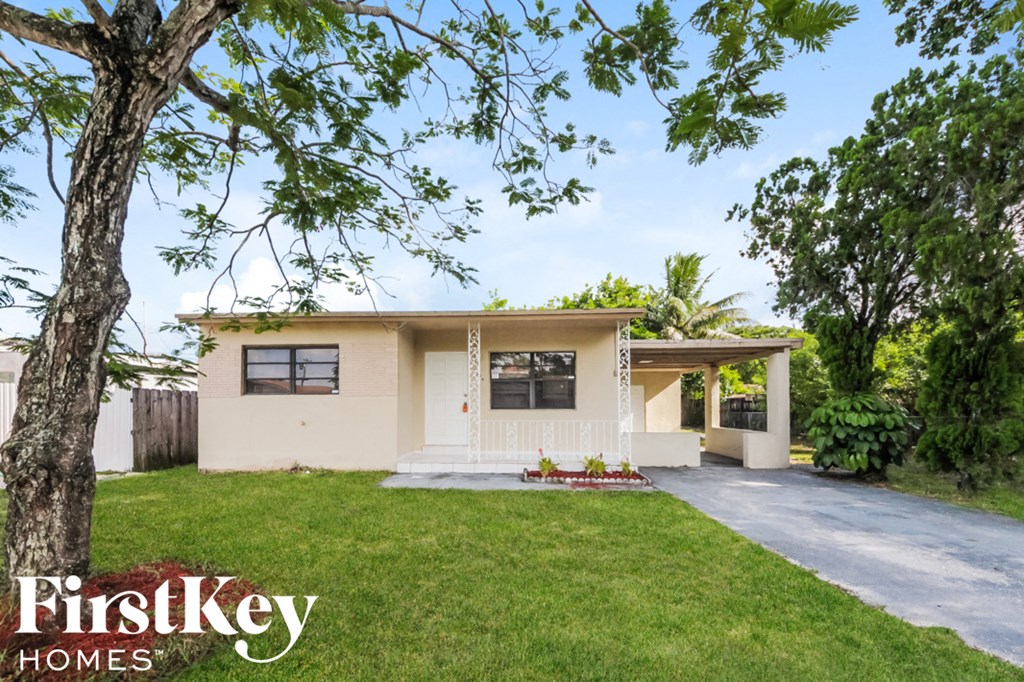 a small white house with a lawn and a tree
