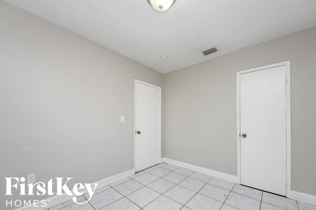 a white room with two doors and a white tile floor