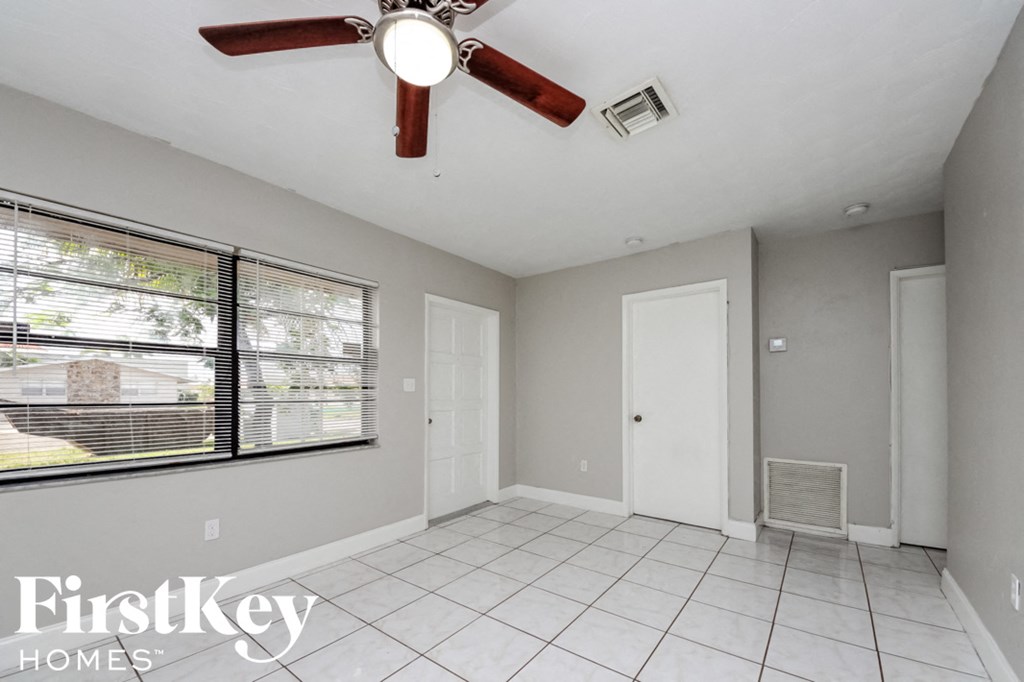 an empty living room with a ceiling fan and a window