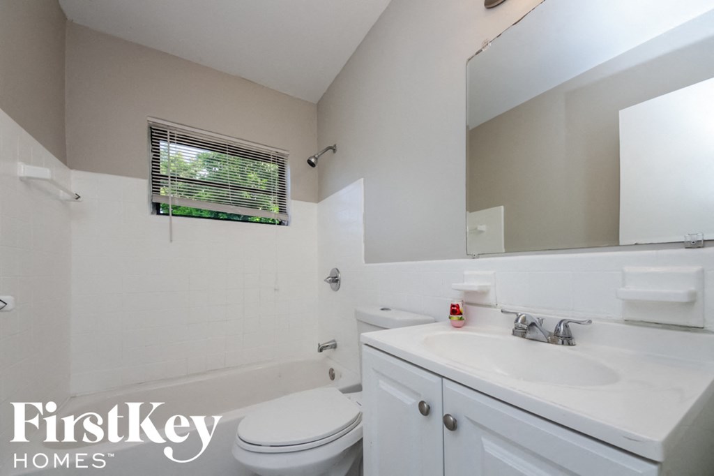 a white bathroom with a sink toilet and a mirror