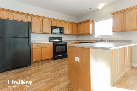 a kitchen with wooden cabinets and a black refrigerator