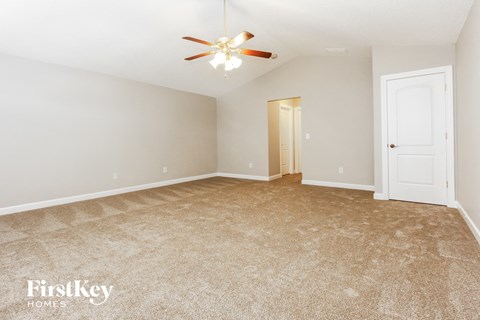 a spacious living room with carpet and a ceiling fan