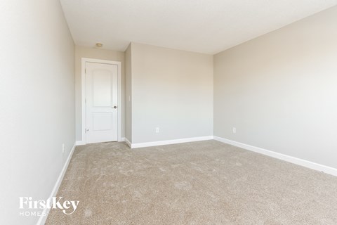 a spacious bedroom with carpet and a white door