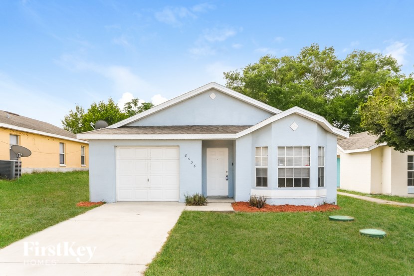 A blue house with a white garage door is for sale.