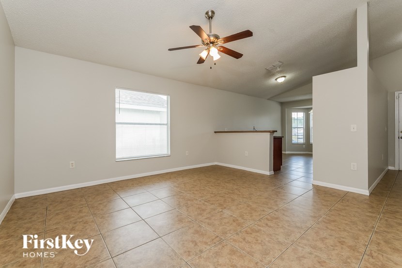 A spacious room with a ceiling fan and tiled floor.