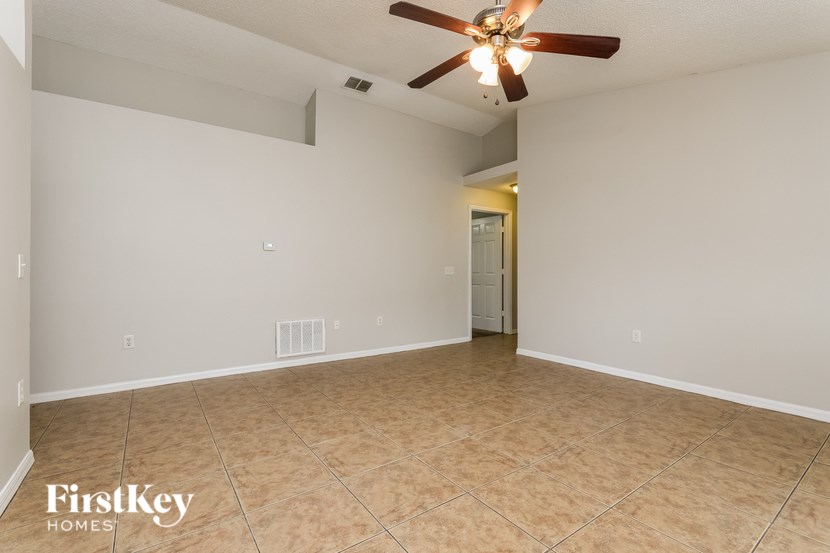 A spacious room with a ceiling fan and tiled floor.