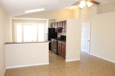 A kitchen with brown cabinets and a black fridge is visible.