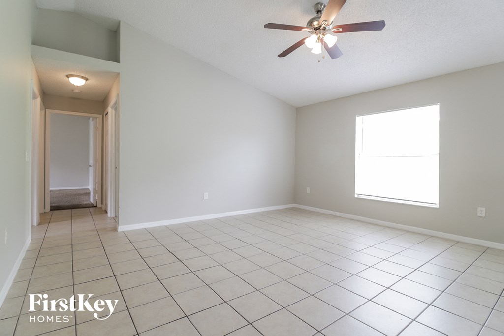 a spacious living room with tile flooring and a ceiling fan