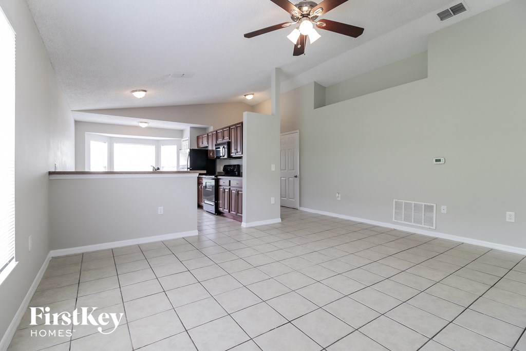 an empty kitchen and living room with a ceiling fan