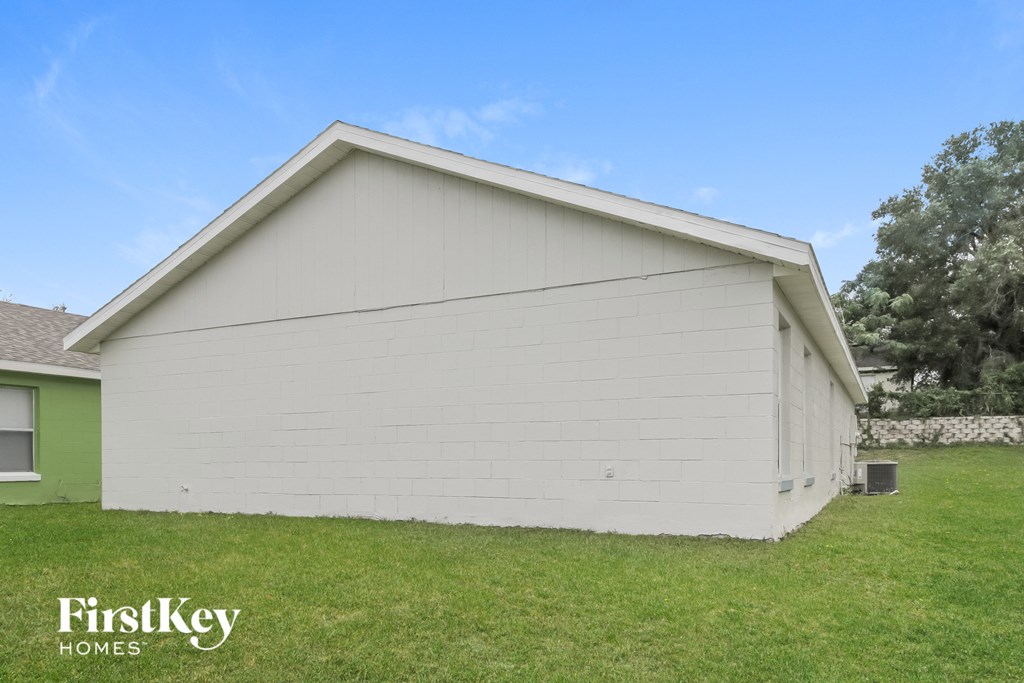 the backyard of a home with white siding and green grass