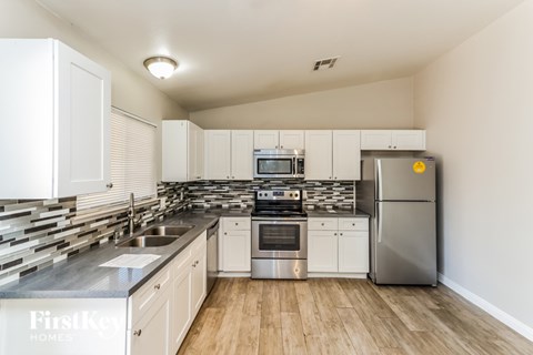 A kitchen with white cabinets and a stainless steel refrigerator.