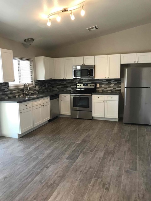 A kitchen with white cabinets and a black countertop.