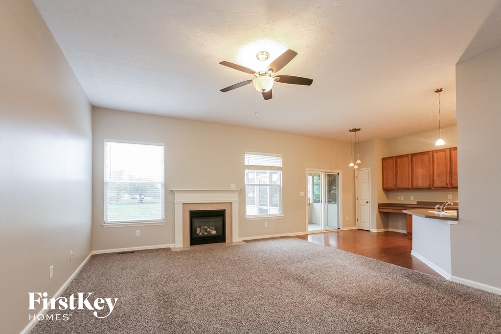 an empty living room with a fireplace and a ceiling fan