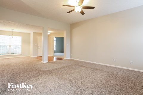 a spacious living room with carpet and a ceiling fan