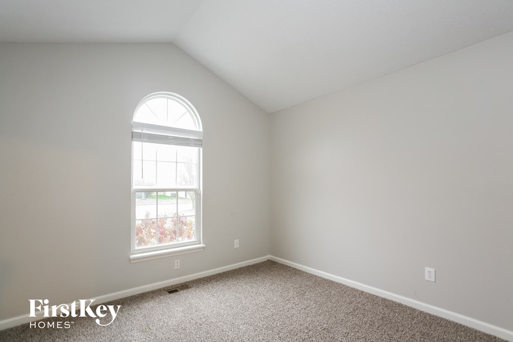 a bedroom with white walls and a window