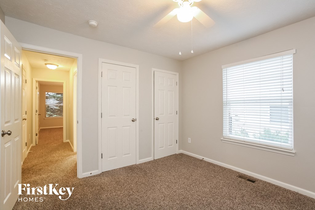 a bedroom with two closets and a window and a carpeted floor