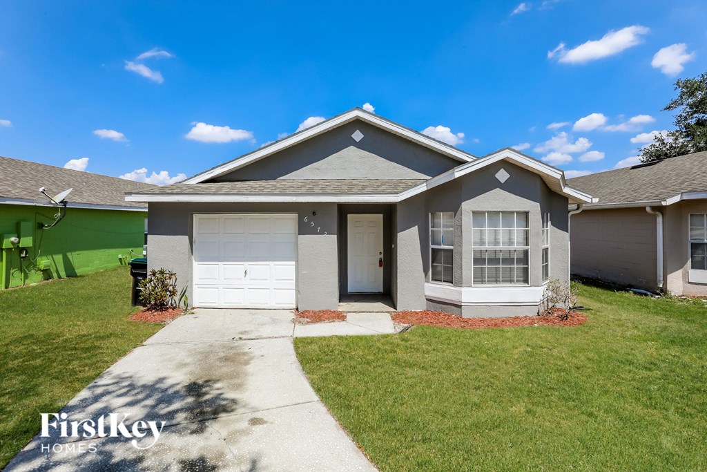 A house with a grey roof and a white garage door is for sale.