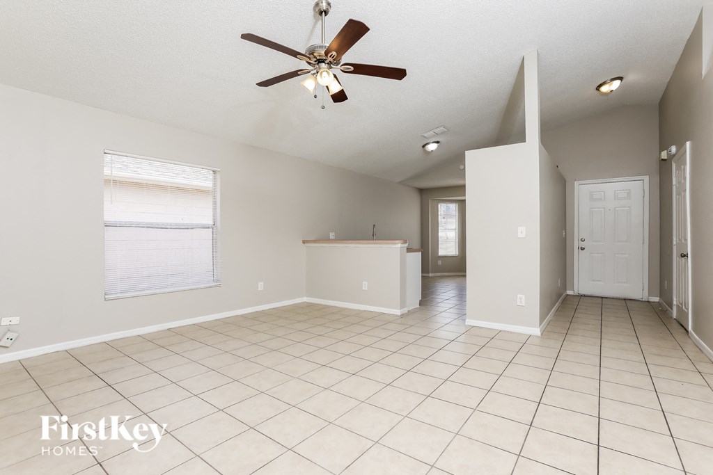 A spacious room with a ceiling fan and tiled flooring.