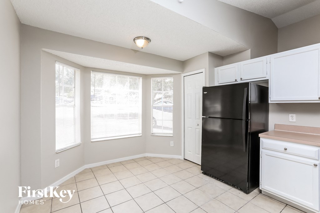 A kitchen with a black fridge and white cabinets.