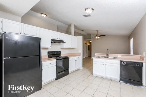 A kitchen with white cabinets and a black fridge.