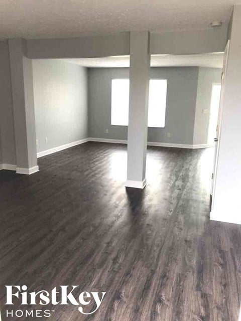 an empty living room with gray walls and wood floors