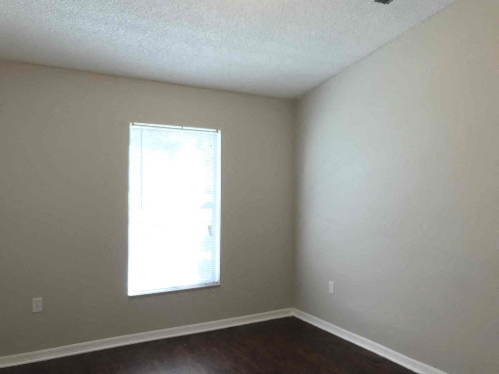 A room with a window and a wooden floor.