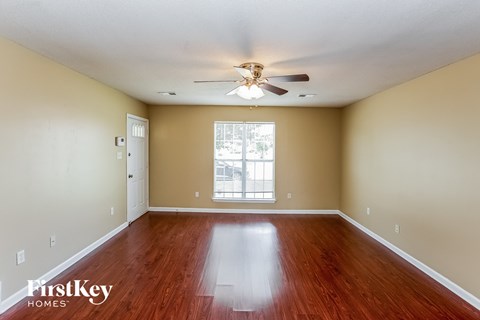 A spacious room with a ceiling fan and wooden flooring.