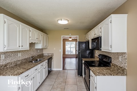 A kitchen with white cabinets and granite countertops.