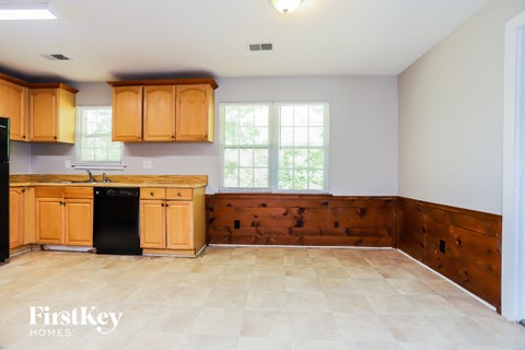 A kitchen with wooden cabinets and a black fridge.