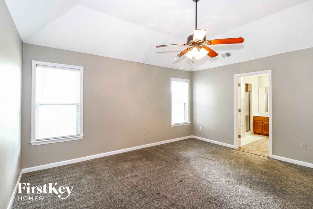 a living room with a carpet and a ceiling fan