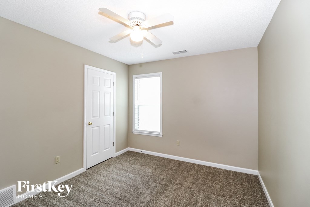 an empty room with a ceiling fan and a white door