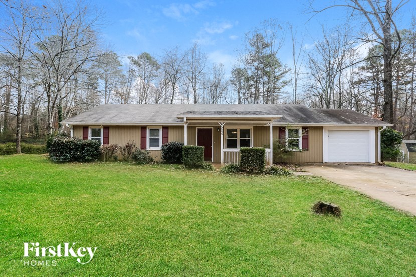 A house with a brown roof and a white garage door is surrounded by trees.