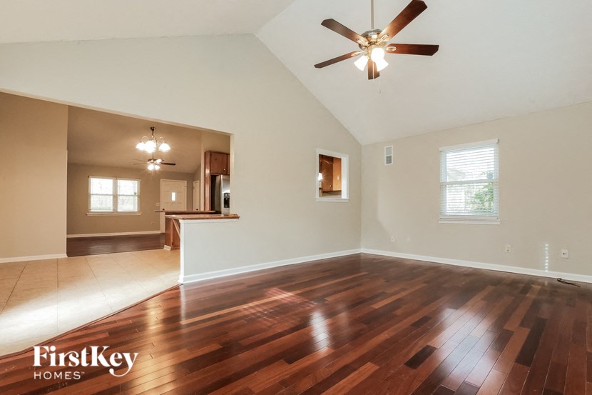 A spacious room with wooden floors and a ceiling fan.