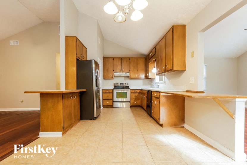 A kitchen with wooden cabinets and a black refrigerator.