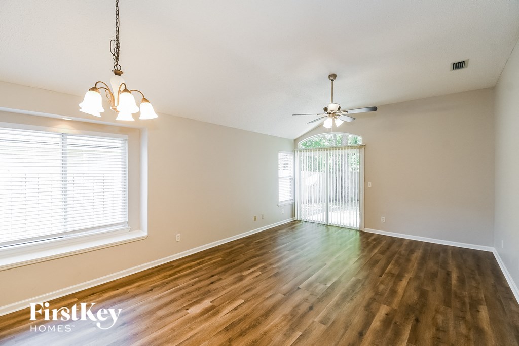 an empty living room with wood floors and a ceiling fan