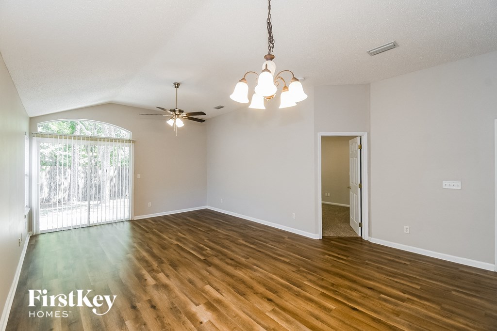 an empty living room with wood floors and a ceiling fan