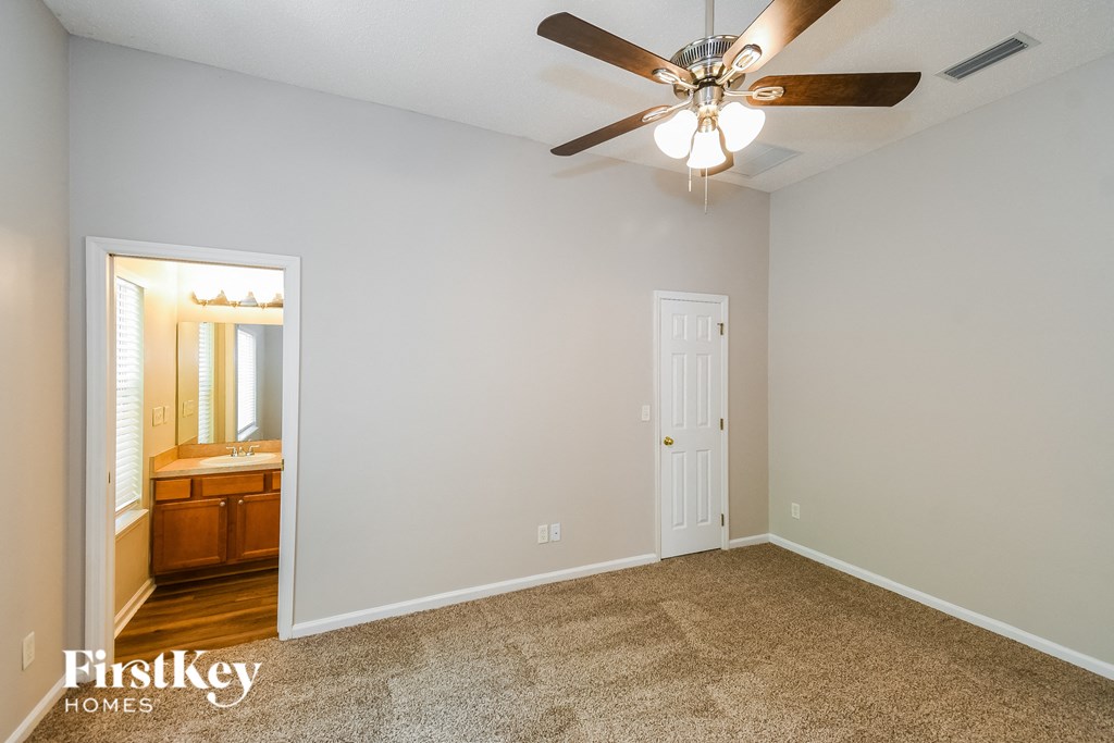 a bedroom with a ceiling fan and a door to a bathroom