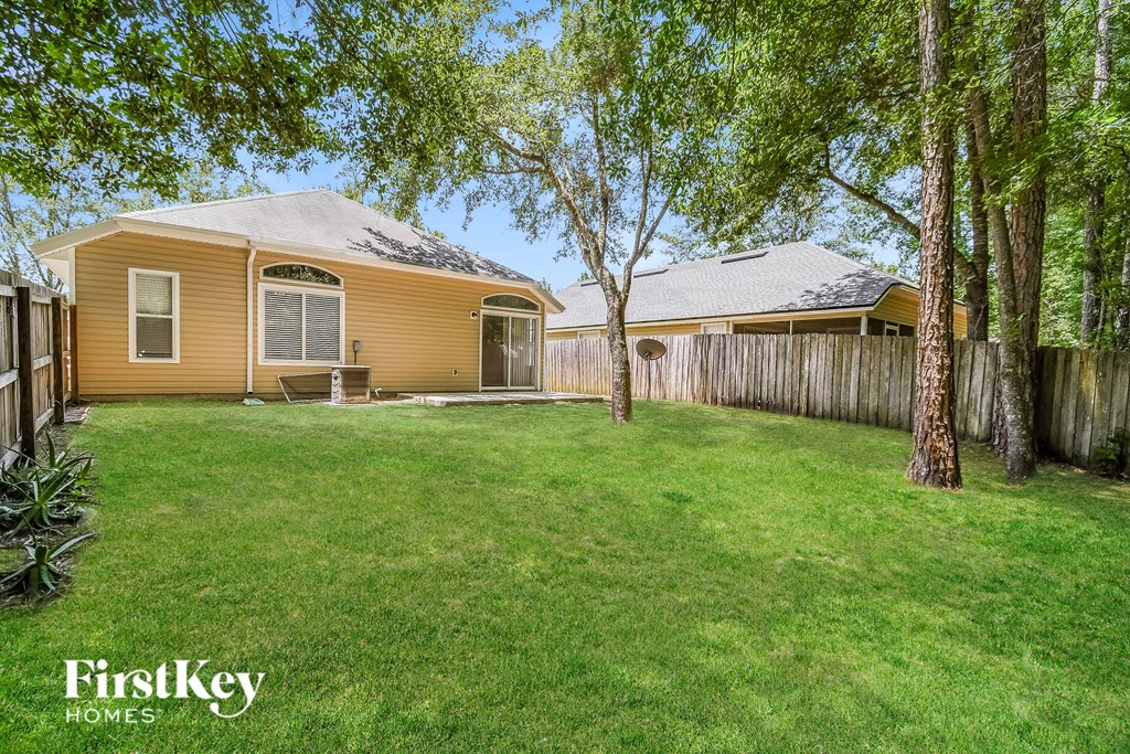 a backyard with a yellow house and a wooden fence
