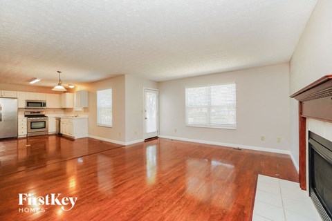 an empty living room and kitchen with wood floors