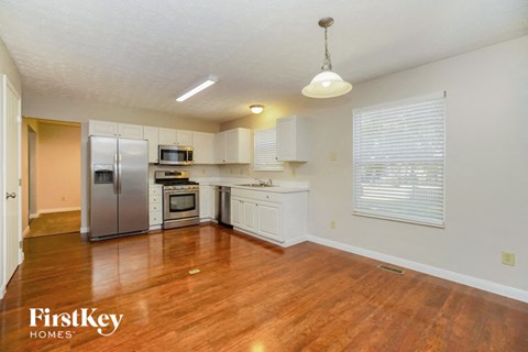 a kitchen with a wooden floor and a stainless steel refrigerator
