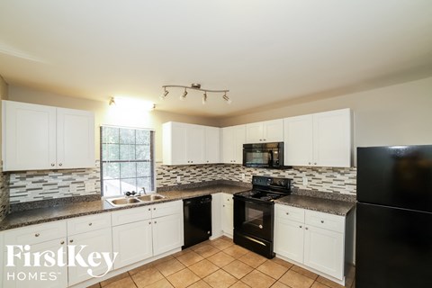 A kitchen with white cabinets and a black refrigerator.