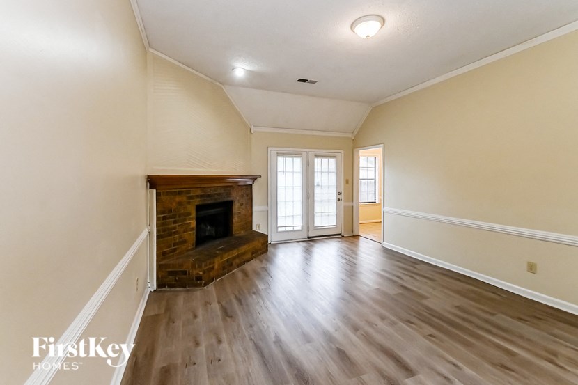 a empty living room with a fireplace and wooden floors