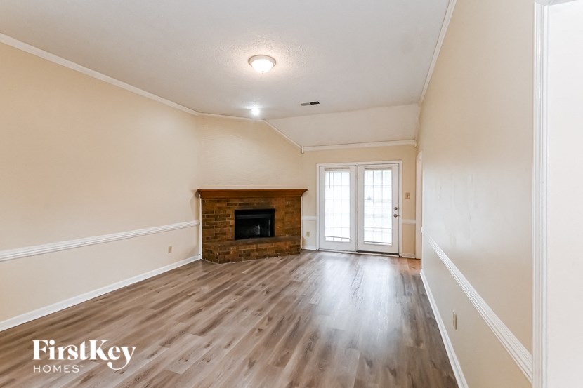 an empty living room with a fireplace and wooden floors