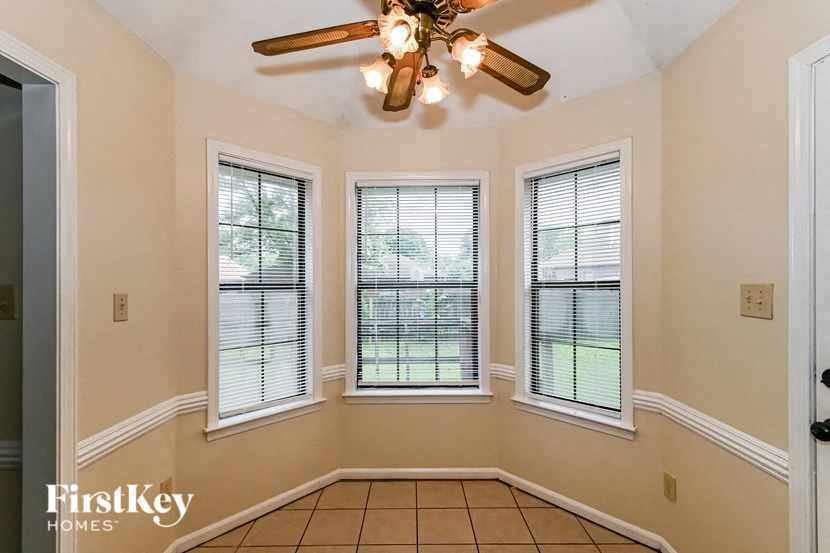 an empty living room with a ceiling fan and three windows