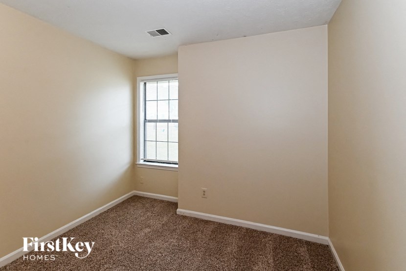 a bedroom with a window and a carpeted floor