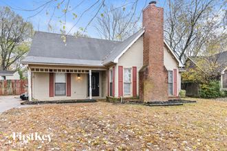 the front of a house with a brick chimney and a yard with fallen leaves