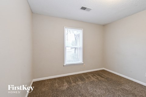 a bedroom with a window and a carpeted floor