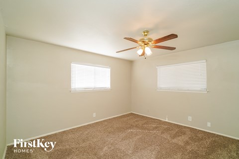 the master bedroom has carpet and a ceiling fan